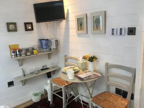 Garden Studio في كرانبروك: طاولة صغيرة مع كرسيين وتلفزيون في الغرفة