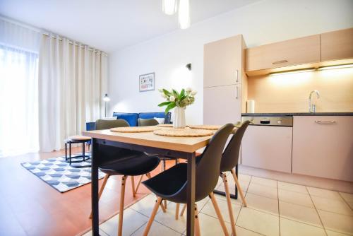 a kitchen and dining room with a table and chairs at Apartamenty Na Wyspie - Baltic Park - Apartamenty z sypialnią i parkingiem - ul Uzdrowiskowa 24-34 in Świnoujście