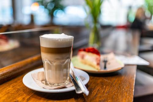 a glass of coffee on a table with a piece of cake at Henriettas Sleeping in Ulm