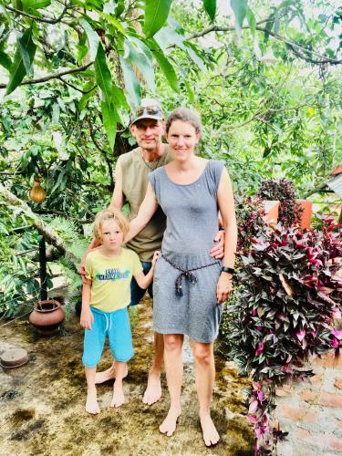a man and a woman and a child standing in a garden at Bindu Homestay in Wellawaya