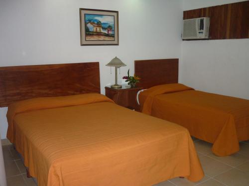 2 Betten in einem Hotelzimmer mit orangefarbener Bettwäsche in der Unterkunft Hotel El Bramadero in Liberia