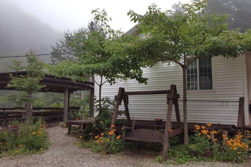a house with a bench and a tree in front of it at Blue Sky Milky Way Pension in Yangyang