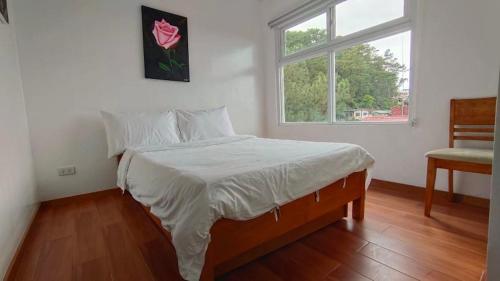 1 dormitorio con cama, ventana y silla en RiCio Haus, en Baguio