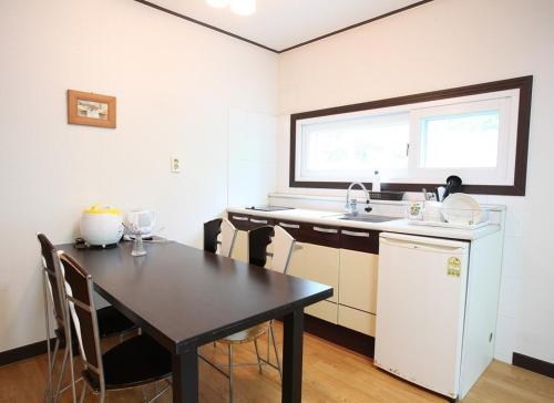 a kitchen with a black table and a white refrigerator at Blue Sky Milky Way Pension in Yangyang