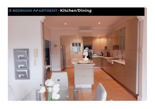 a kitchen with white cabinets and a glass table at Ocean Aspect and Central to CBD - CoSheirm Apartments On Merri in Warrnambool