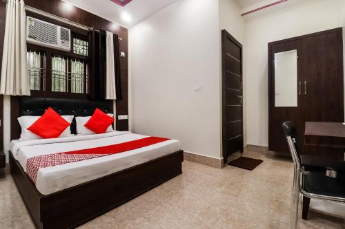 Schlafzimmer mit einem Bett mit roten Kissen und einem Schreibtisch in der Unterkunft OYO Hotel Chandra in Itaunja