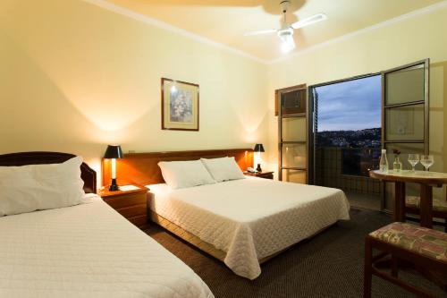 a hotel room with two beds and a window at Hotel Lopes Caxambu in Caxambu