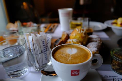 a cup of coffee on a table with a plate of food at Settecento Hotel in Presezzo