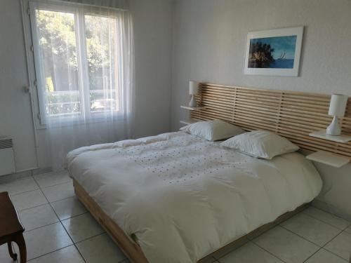 un grand lit blanc dans une chambre avec une fenêtre dans l'établissement 3P PARC DE DIANE PISCINE, à Antibes