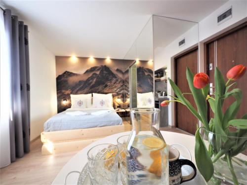 - une chambre avec un lit et une table ornée d'un vase de fleurs dans l'établissement Gawra Apartament Studio, à Zakopane