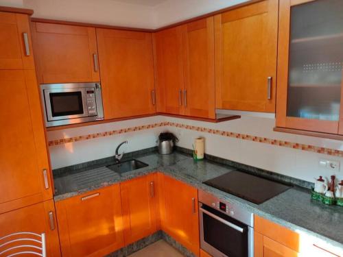 a kitchen with wooden cabinets and a sink and a microwave at Piso espectacular al lado de las playas en Portonovo in Sanxenxo