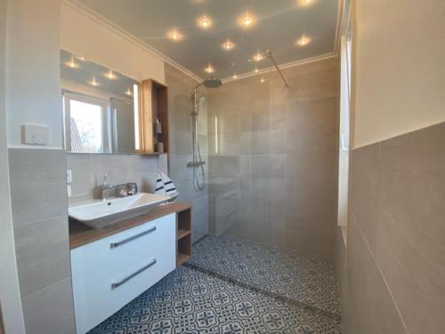 ein Badezimmer mit Waschbecken, Spiegel und Dusche in der Unterkunft Villa Senator-Marstall in Travemünde