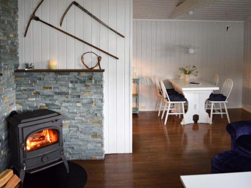 a living room with a fireplace and a table and a stove at Holiday home Utvik IV in Utvik