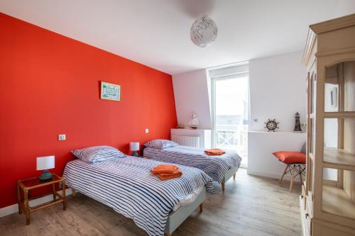 duas camas num quarto com uma parede vermelha em Ti Kasino em Pléneuf-Val-André