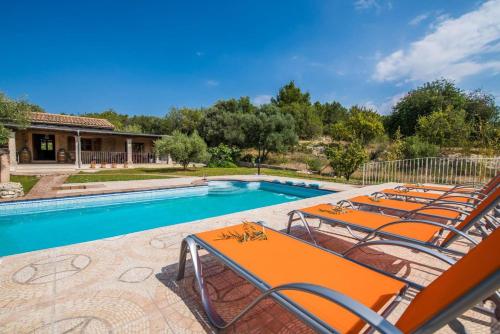 a pool with orange lounge chairs next to a house at Ideal Property Mallorca - Ses Comes in Selva