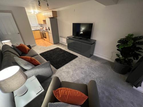 a living room with a couch and a flat screen tv at Cotswold apartment with private parking! in Stow on the Wold