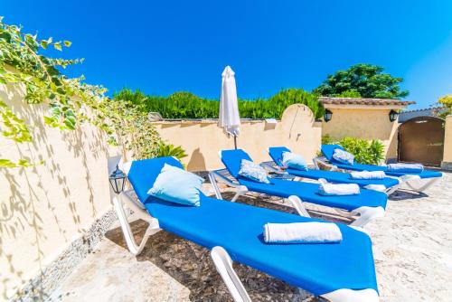 a row of blue lounge chairs and an umbrella at Sort Llarga in Pollença