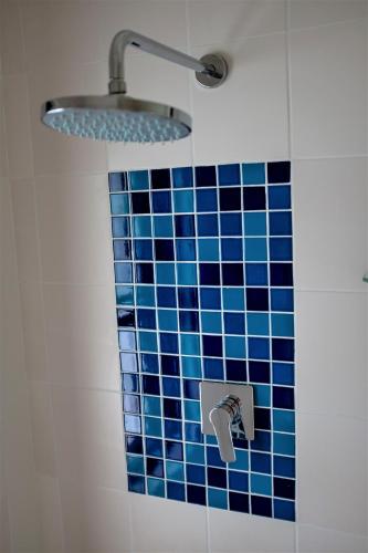 a bathroom with a blue tiled wall with a shower at Boulders Beach House in Simonʼs Town