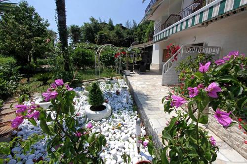 a garden with flowers and a pond in front of a building at Guesthouse Villa Stanger 2 in Lovran
