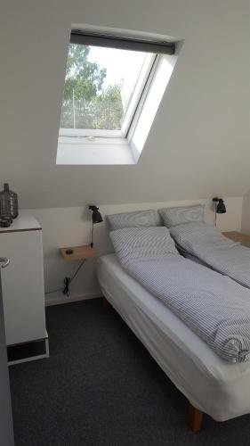 a white bedroom with a bed with a window at Elleholm A in Odense