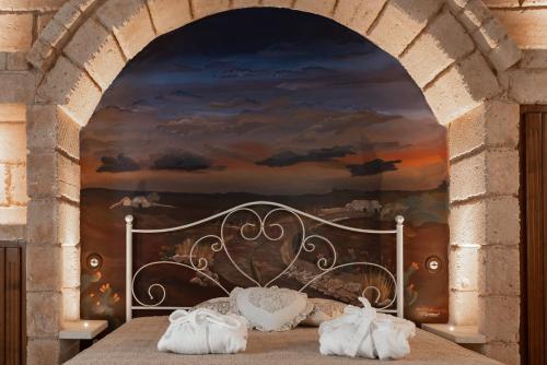 a bedroom with a bed with a painting on the wall at Donna Fiora Antica Dimora in Alliste
