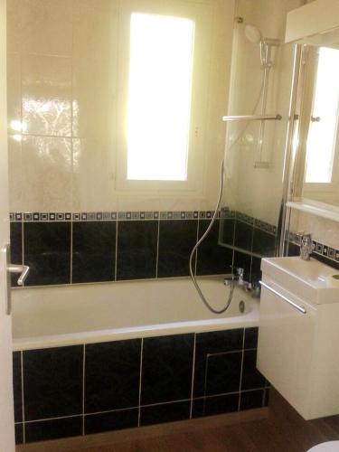 La salle de bains est pourvue d'une baignoire, d'une fenêtre et d'un lavabo. dans l'établissement Appartement confortable à Houlgate de 25 m² avec jardin, à Houlgate