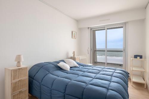 a bedroom with a blue bed with a view of the ocean at Magnifique vue mer pour un sejour Baulois in La Baule