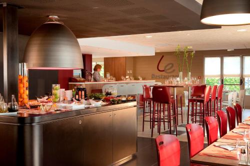 a restaurant with a bar with red chairs and tables at Campanile Valenciennes - Petite-Forêt in Petite Forêt