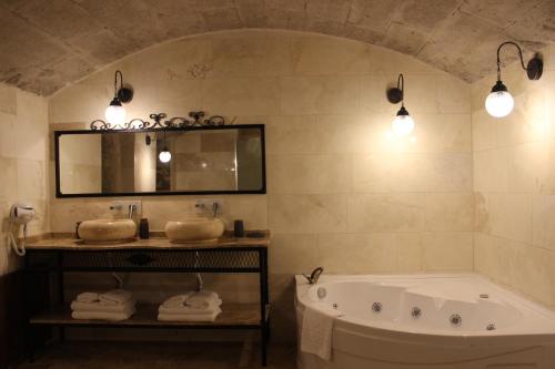 a bathroom with a tub and two sinks and a mirror at Kayra Cave Suites in Goreme