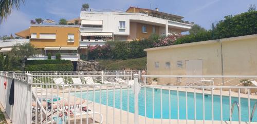 une piscine avec des chaises et un bâtiment dans l'établissement 3P PARC DE DIANE PISCINE, à Antibes