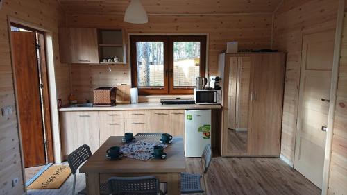 eine Küche mit einem Tisch und einem weißen Kühlschrank in der Unterkunft Zakątek Borsk, Jasnochówka 2, domek 37 in Borsk
