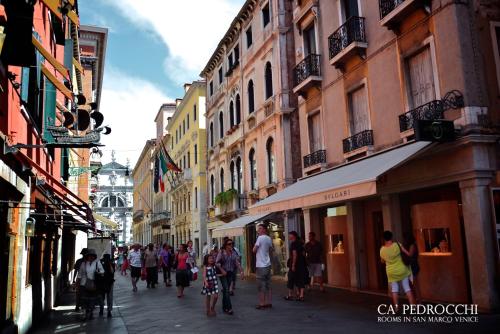 a group of people walking down a street with buildings at Ca' Pedrocchi in Venice