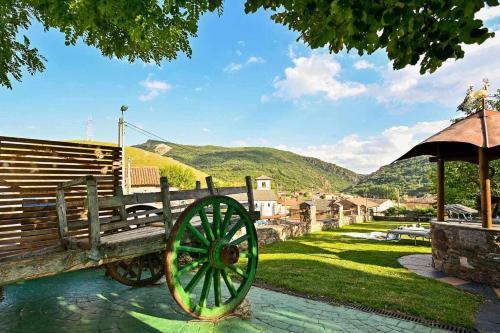 a wooden bench with a wheel sitting next to a hill at Casa rural la castañona in Buiza