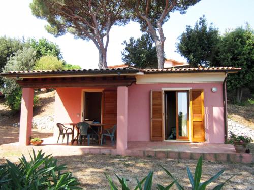 una pequeña casa rosa con mesa y sillas en Villetta Giada, en Capoliveri