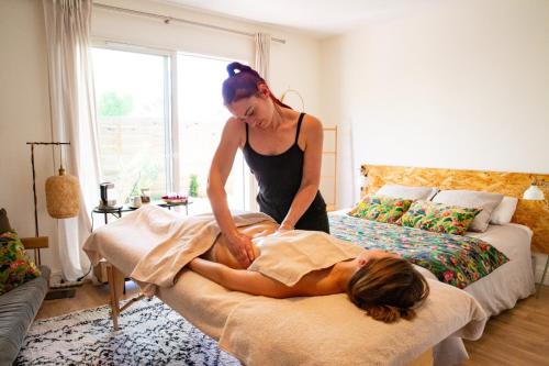 a woman giving a woman a massage on a bed at KER AMICE in Saint-Loubès