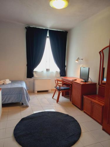 a bedroom with a bed and a desk with a television at River Park Hotel in Ameglia