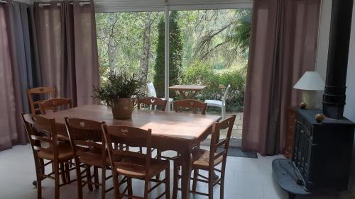 uma mesa de jantar com cadeiras e uma grande janela em Gîte Maison des Poules em Marvejols