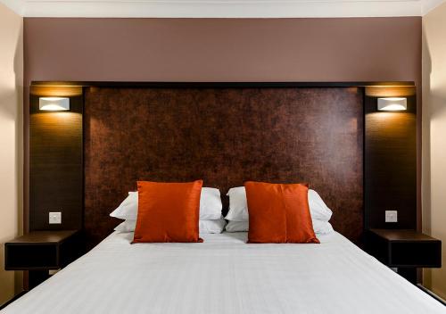 a bedroom with a large bed with orange pillows at Dragonfly Hotel Colchester in Colchester