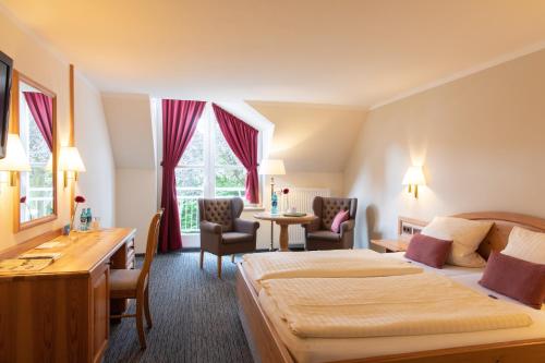 a hotel room with two beds and a desk at Hotel Altes Stadthaus in Westerstede