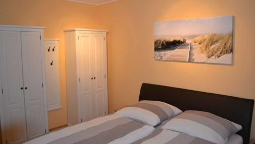 ニーンドルフにある_DKK1e_ Ferienwohnung Seepferdchenのベッドルーム1室(ベッド1台付)が備わります。壁には絵画が飾られています。