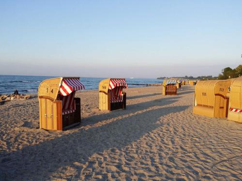 a row of beach shelters on a sandy beach at _DKK1e_ Ferienwohnung Seepferdchen in Niendorf