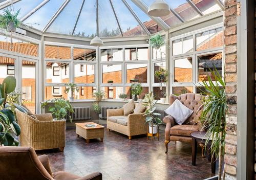 a conservatory with couches and chairs and windows at Dragonfly Hotel Colchester in Colchester