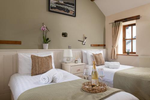 アベルゲレにあるBeautiful Countryside cottage on the North Wales Coastのベッド2台とシャンパン1本が備わるホテルルームです。