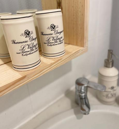 a bathroom sink with three cups on a shelf at Blue Bay Apartment in Setúbal