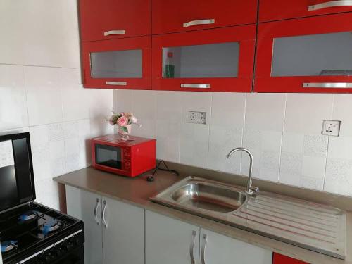 cocina con fregadero y microondas rojo en Cheerful 2-bedroom Apartment with free parking, en Kumasi