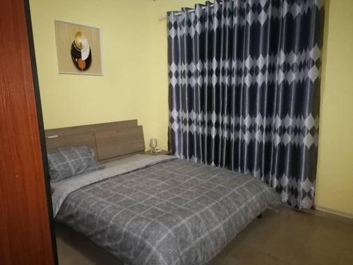 a small bedroom with a bed and a curtain at Cheerful 2-bedroom Apartment with free parking in Kumasi