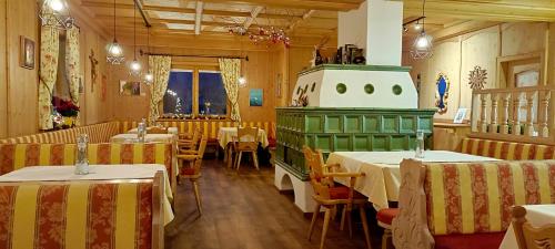 a restaurant with tables and chairs and a green stove at Alpenhof Wohlfühlpension in Obsteig