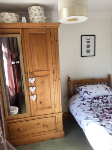a bedroom with a wooden cabinet next to a bed at Dunedin House Nedderton Village Bedling in Hepscott