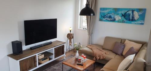 a living room with a couch and a flat screen tv at Ferienhaus Strandjuwel in Dranske