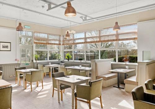 a restaurant with tables and chairs and windows at Dragonfly Hotel King's Lynn in Kings Lynn